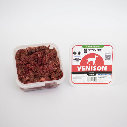 Container of venison pet food next to its packaging on a white background